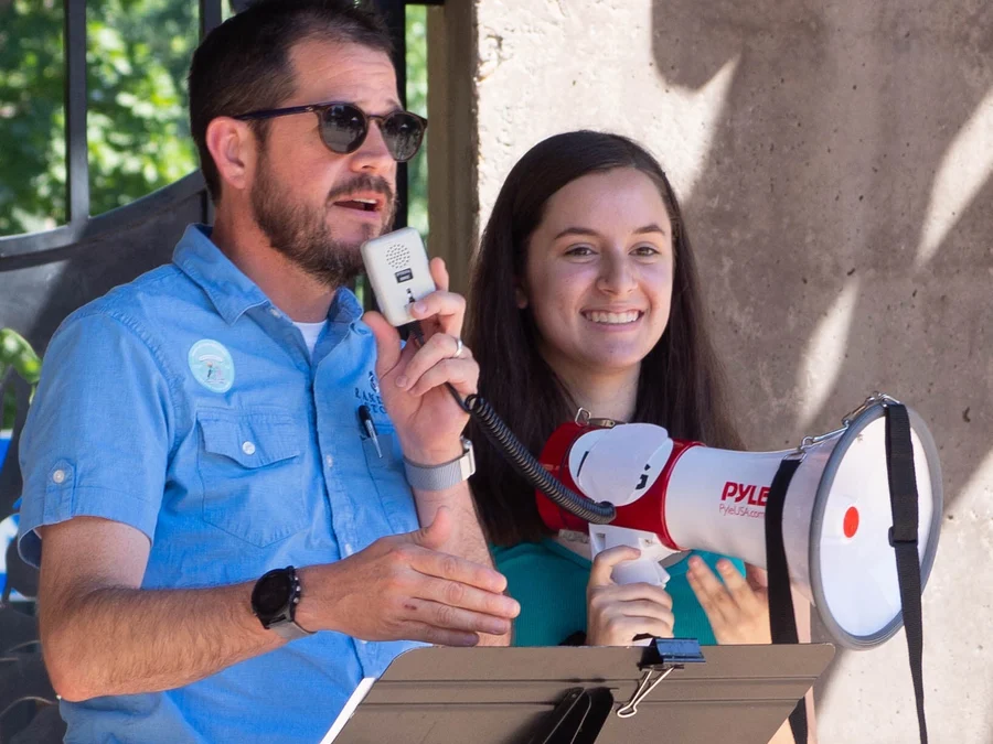 Randall Stone speaking beside a young participant with a megaphone at an LGBTQ+ community performance and event